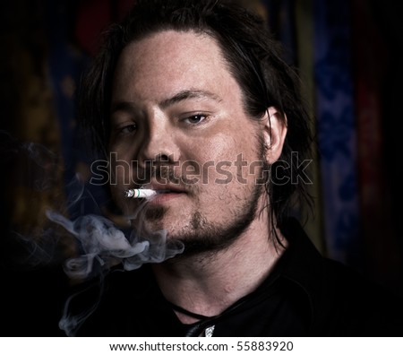A gritty man smoking a cigarette - image vignetted and contrast pushed to increase the gritty mood of the image.