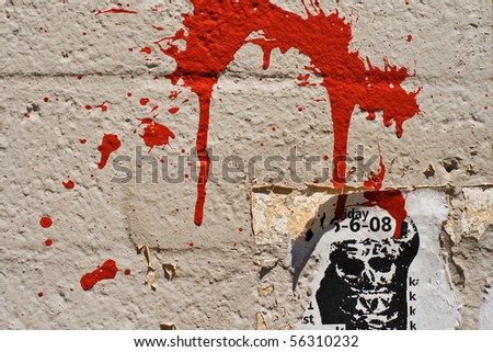 A splash of red paint on a brick wall with a torn old concert poster - very urban abstract kind of image, good for backgrounds.