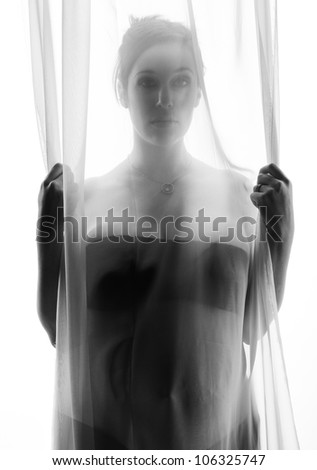Beautiful pregnant woman behind a sheer curtain.