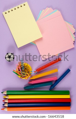 Crayons, paper, pencil, clips. At lilac background. The model for posting your pictures or inscriptions.