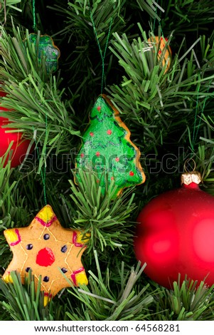 A fragment of a Christmas tree. Christmas tree decorated with Christmas cookies and balloons. Cookies are hand-painted. Spruce artificial. The balls are red. Cookies of different shapes.