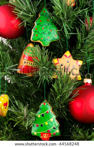 A fragment of a Christmas tree. Christmas tree decorated with Christmas cookies and balloons. Cookies are hand-painted. Spruce artificial. The balls are red. Cookies of different shapes.