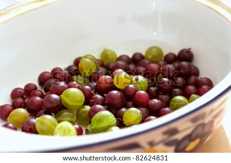 In the bowl of fresh gooseberries are. Ceramic ware, with a pattern. Gooseberry green and red.