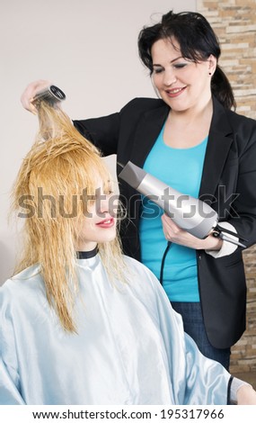 Hairdresser dries the hair dryer blond long hair