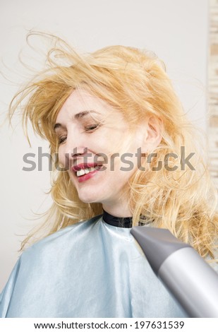 Hairdresser dries the hair dryer blond long hair