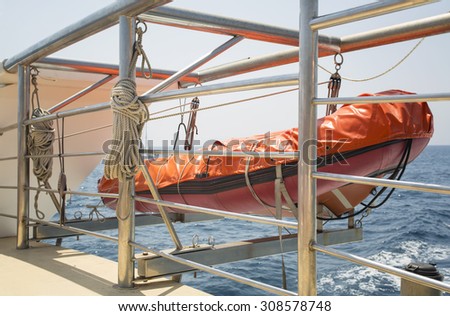orange lifeboat hanging on ship at sea