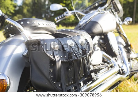 Rear part of motorcycle. Black leather bag.