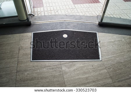 Black with metal frame mat on the gray stone floor near metal glass sliding door