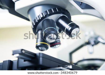 Scientific microscope lens close-up in laboratory white interior. A microscope is an instrument used to see too small objects