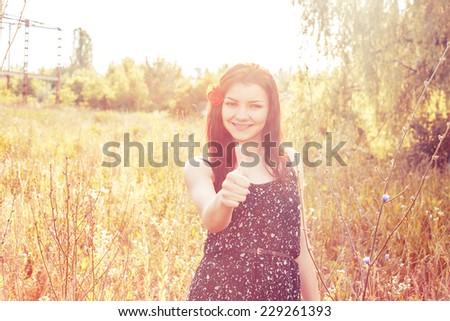 sunny portrait of a woman thumbs up with a poppy in her hair