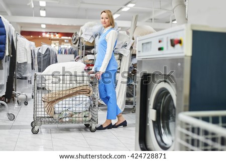 Girl Laundry worker rolls a cart with clean stuff at the dry cleaners