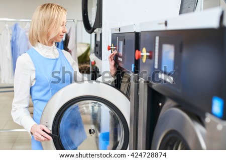 Girl Laundry worker selects a wash program at the dry cleaners