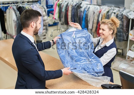 Girl worker Laundry man gives the client clean clothes at the dry cleaners