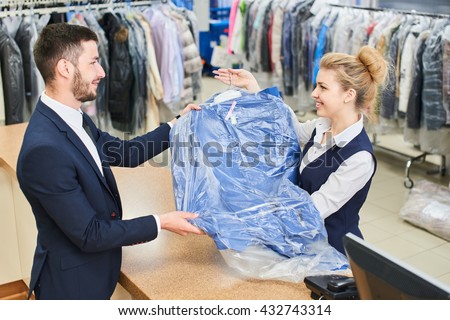 Girl worker Laundry man gives the client clean clothes at the dry cleaners