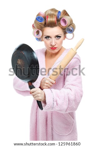 Housewife in pink bathrobe with rolling pin and frying pan on white background