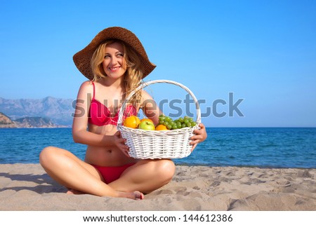 Attractive woman with basket of fruits on a seacoast