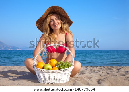 Attractive woman with basket of fruits on a seacoast