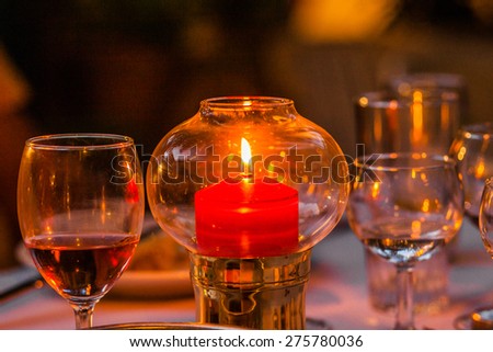 Candle stick in a glass bubble with class of wine on the side