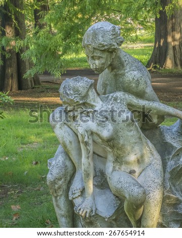 Front view of a couple about to kiss gray sculpture against trees and plants background taken in botanical garden of Montevideo, Uruguay.