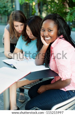 Young lady smiling with friends studying in the background