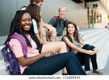 Young woman smiling with friends in the background on stairs