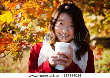 Asian woman drinking a warm drink in the fall
