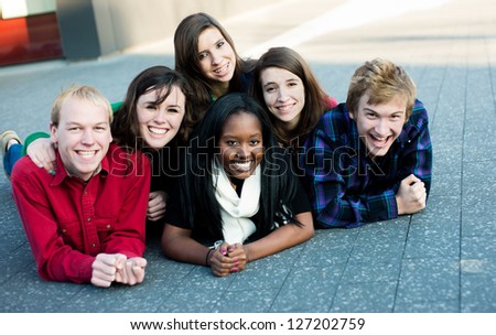 Group of diverse students outside smiling in a pyramid