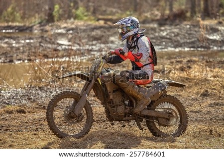 Motocross driver on muddy offroad track and wet terrain at cross country competition in Parola, Finland.