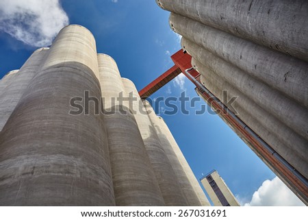 Factory exterior with high concrete grain silos in Finland on a sunny spring day. This majestic old industrial building is not in use anymore. Very strong perspective from low angle view.