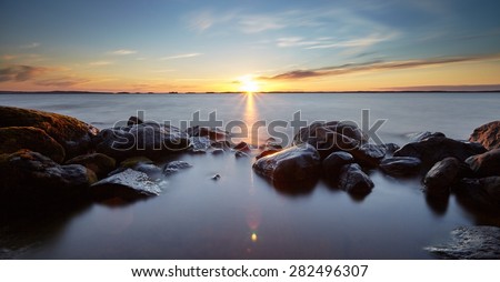 Peaceful landscape with very long exposure and sunset. Silky smooth water flows around the rocks in the water.