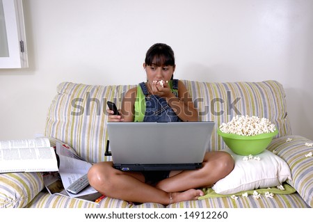 Girl of generation Y doing many things at the same time (calling,  watching tv, Surfing the web and eating popcorn)