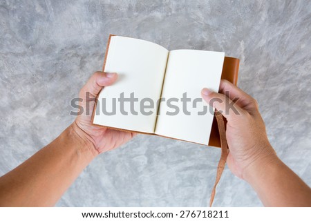 overhead view of hands holding a blank book on gray back ground