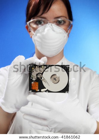 Beautiful young woman in mask hold hard disk drive (focus on hard drive)
