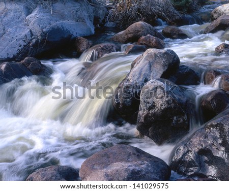 Flowing creek water at flood stage/water falls/Peaceful is the sound of running water in the wilderness. Soothing is the effect on a human being.  It\'s good for the soul.