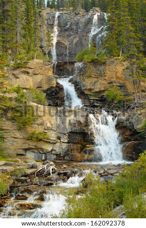 Five tiered water falls in the Rocky Mountains, Canada is still full of snow melt off water. Water falls/The season of fall is in the color of leaves and the rush of water falling adds to the beauty.
