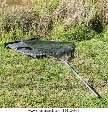 background coarse fishing landing net and changing mat at river side.