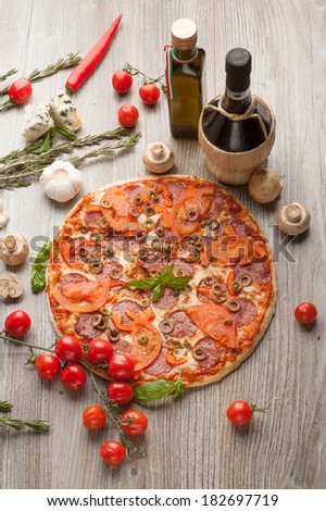 Italian pizza, mozzarella, chedar. Around decomposed products ingredients: olive oil, wine, cherry tomatoes, hot peppers, mushrooms.