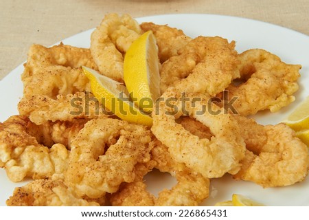 Squid, seafood, lemon, lemon slices deep fried squid rings, seafood laid out on white plate decorated with lemon, linen cloth, fabric texture.