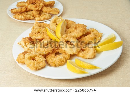 Squid, seafood, lemon, lemon slices deep fried squid rings, seafood laid out on white plate decorated with lemon, linen cloth, fabric texture