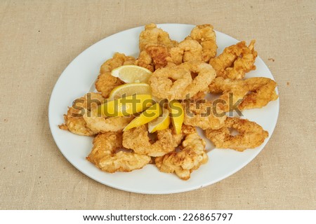 Squid, seafood, lemon, lemon slices deep fried squid rings, seafood laid out on white plate decorated with lemon, linen cloth, fabric texture.