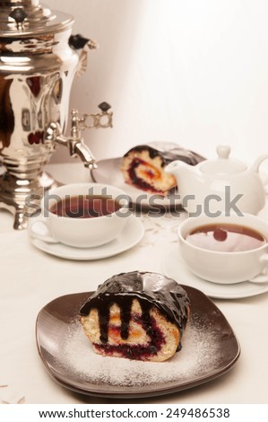 Dessert, roll, biscuit, white cup. Two cups of tea and teapot standing on a table in the background samovar myakgy focus.