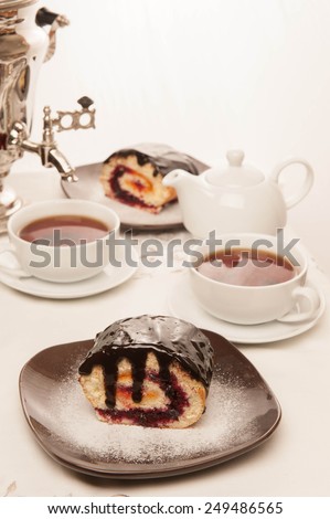 Dessert, roll, biscuit, white cup. Two cups of tea and teapot standing on a table in the background samovar myakgy focus.