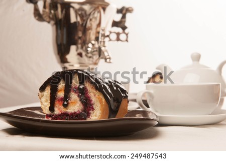 biscuit roulade, biscuit, white cup. Two cups of tea and teapot standing on a table in the background samovar myakgy focus.