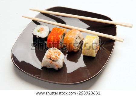 sushi rolls sushi rolls. lie on a black plate five skates and sticks. Photo on a white background.