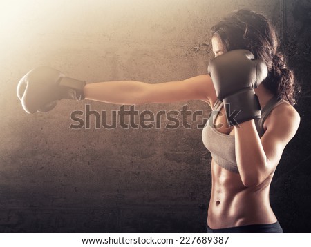 Strong athletic woman with boxing gloves punching