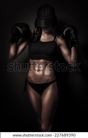 Sexy and fit woman with boxing gloves in the dark