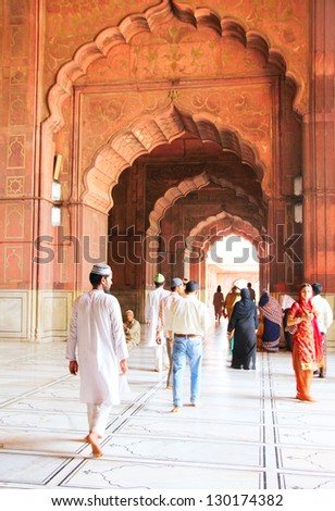 DELHI - JUNE 2012. People go through the gallery at ancient Jama Masjid mosque on June 14, 2012 in Delhi, India. It\'s the largest mosque in North India with millions of visitors each year.
