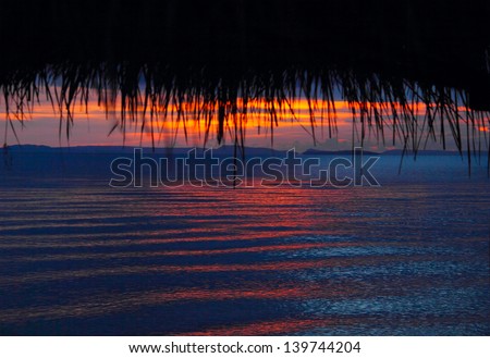 Beautiful scenic view with shadow figure of reed roof against the sunset sea landscape background in Sihanoukville, Gulf of Thailand, South Cambodia. May - 2013