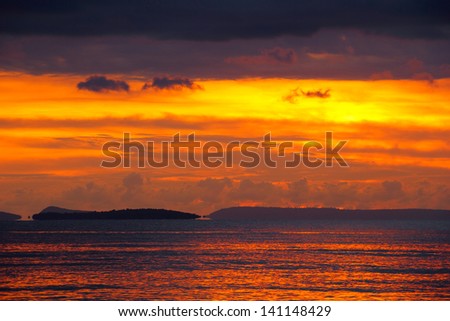 Beautiful scenic landscape with dramatic cloudy sky at sunset above the calm waters of Gulf of Thailand and distant small island near Sihanoukville, Cambodia, South East Asia