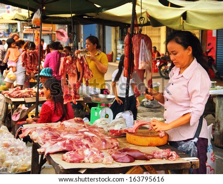 PHNOM PENH/CAMBODIA - MAY 09. Unidentified khmer woman cuts and sales a meat  on may 09, 2013 in Pnom Penh central market, Cambodia, South East Asia